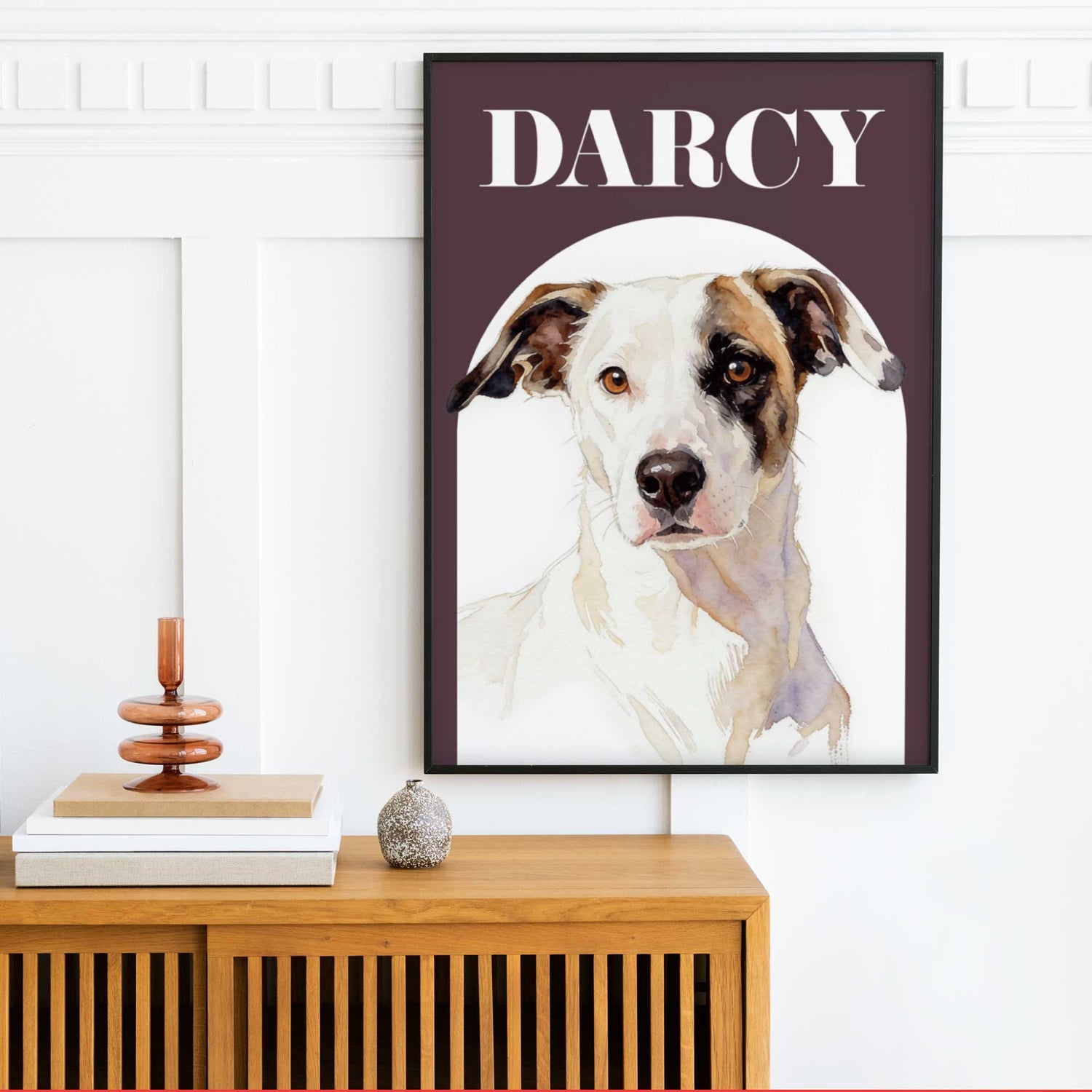 Framed pet portrait of a dog named Darcy on a wall above a wooden cabinet.