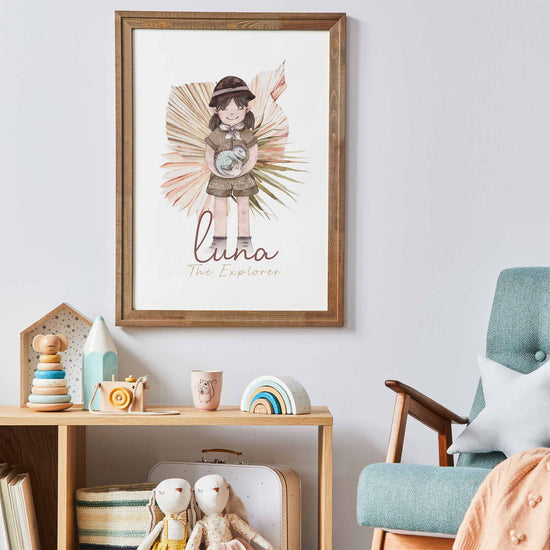 A picture frame of a brunette haired little girl holding a baby dinosaur displayed on the wall of a kids room