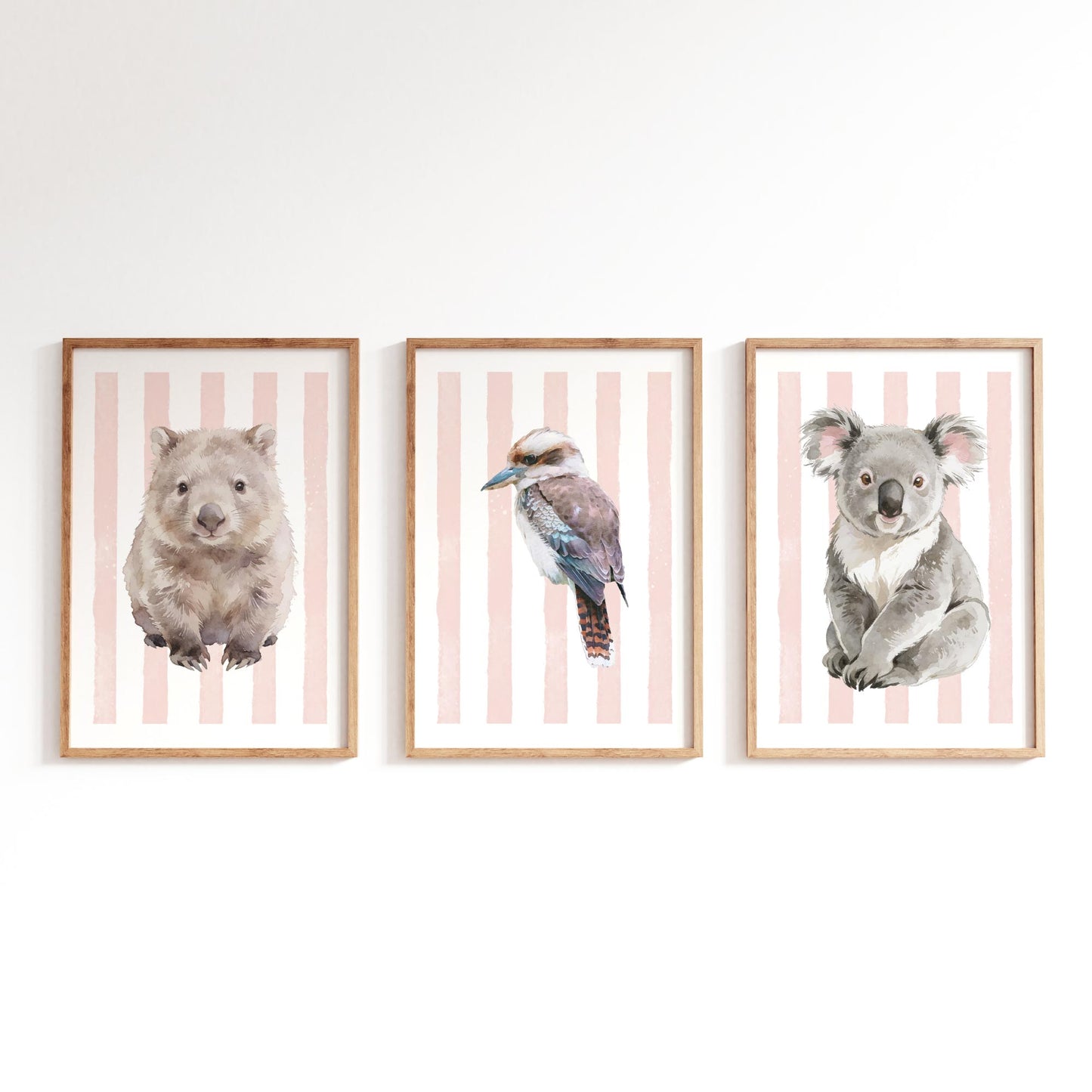 Three framed prints of a wombat, kookaburra, and koala on a striped pink background.