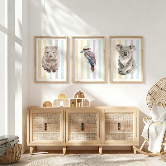 Framed Australian native animal prints on a rainbow striped background on a wall above a wooden cabinet in a bright room.