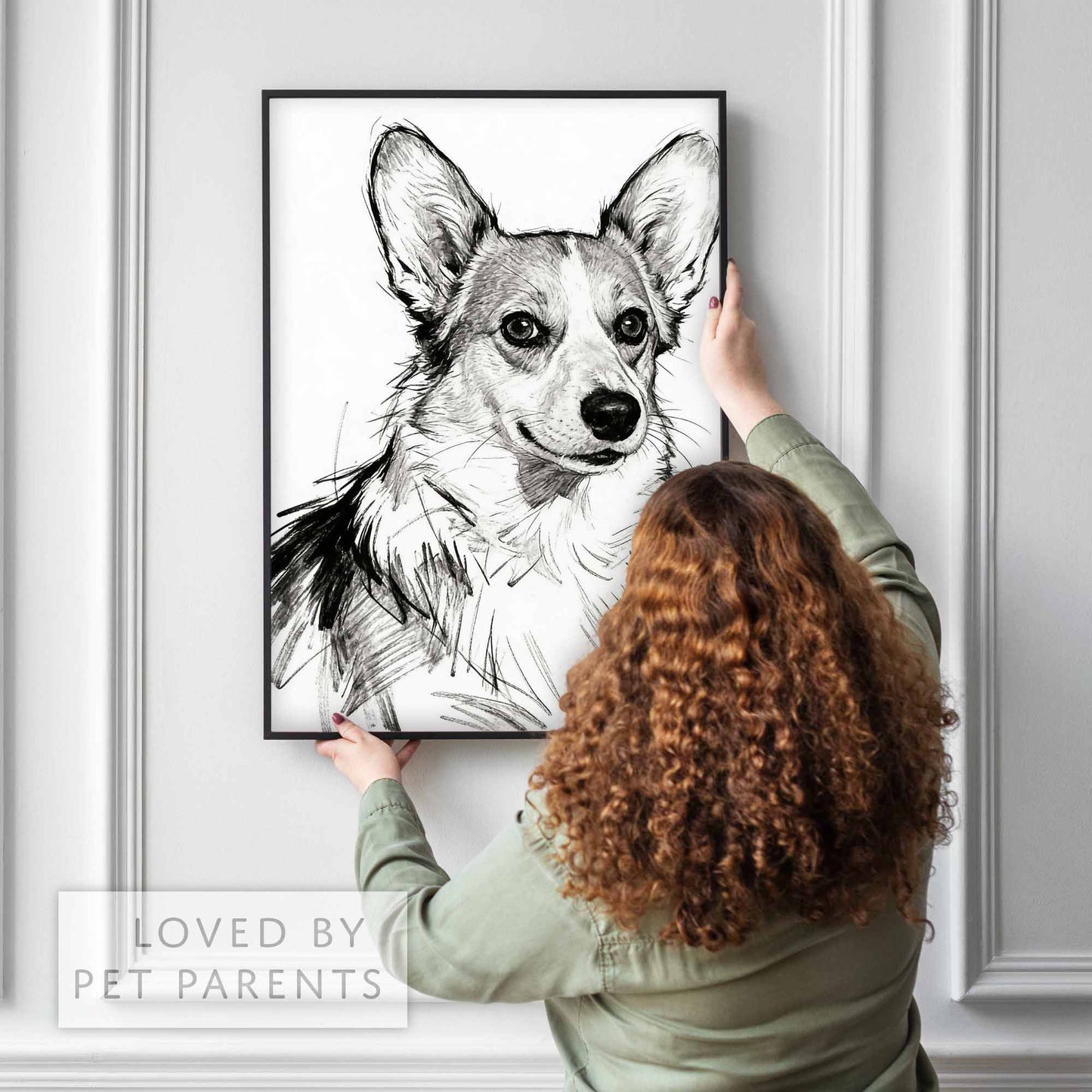 Person hanging framed sketch style pet portrait on wall