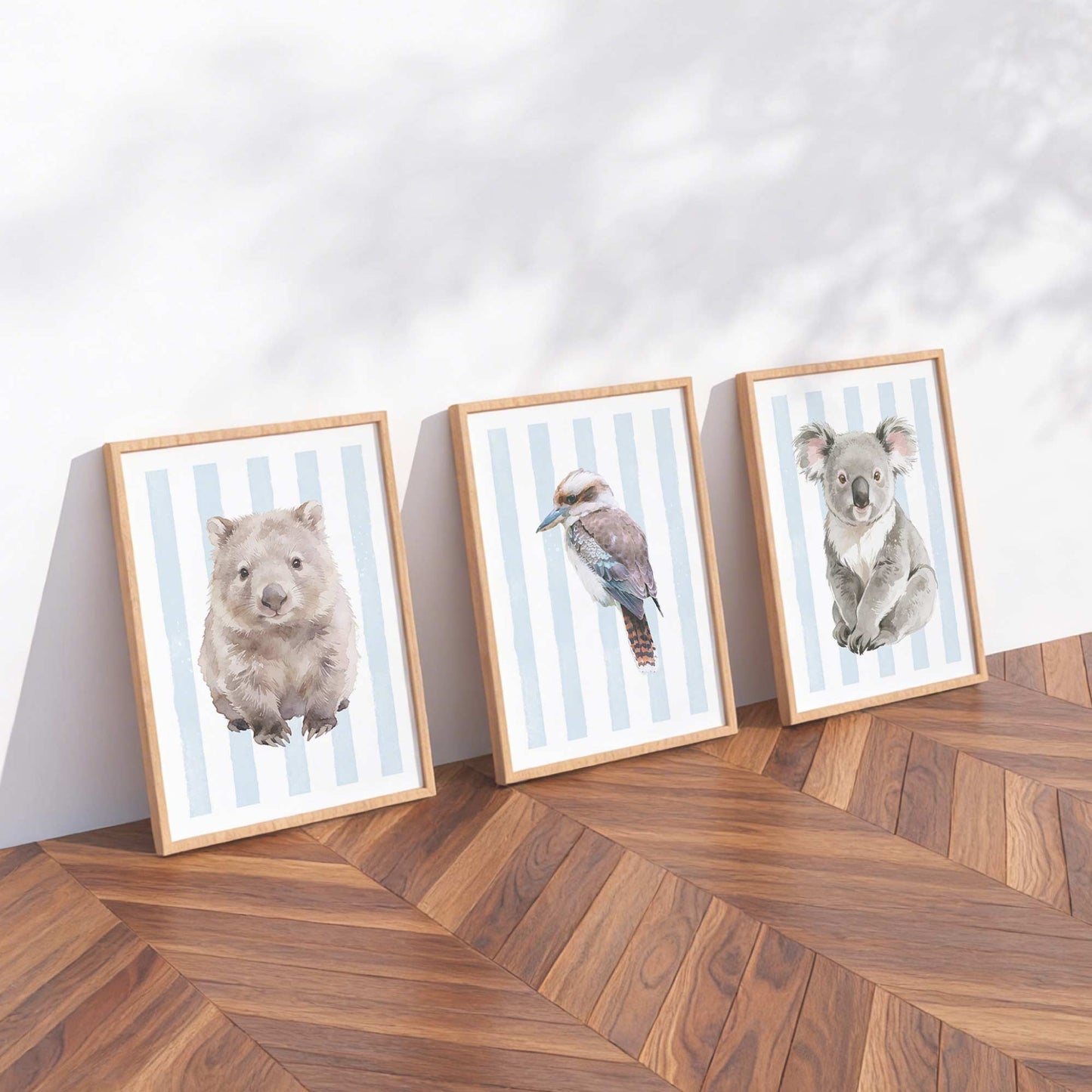 Three framed prints of Australian native animals on a striped blue background on a wooden floor with a white wall background