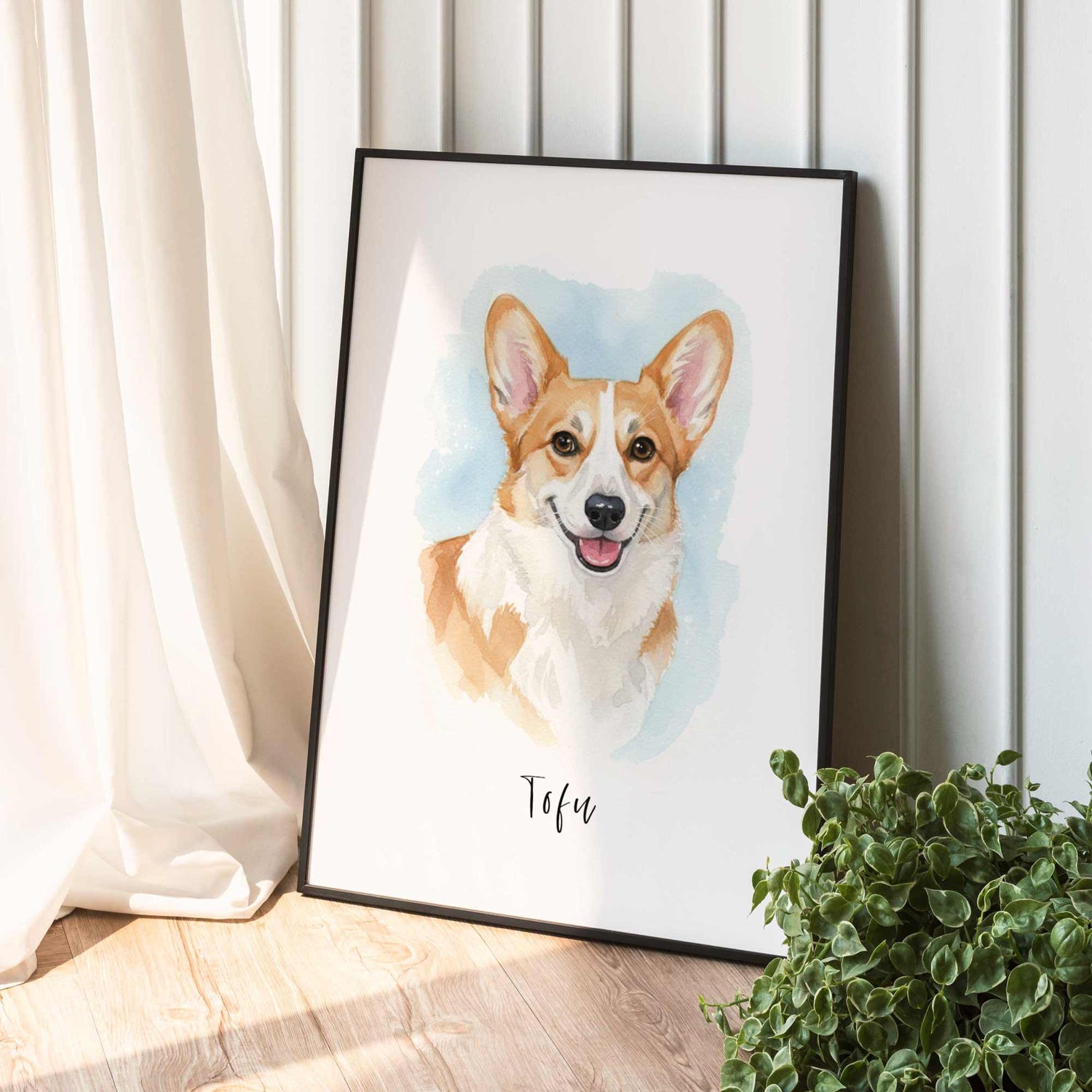 Framed artwork of a corgi dog named Tofu on a white wall with a plant in the foreground.