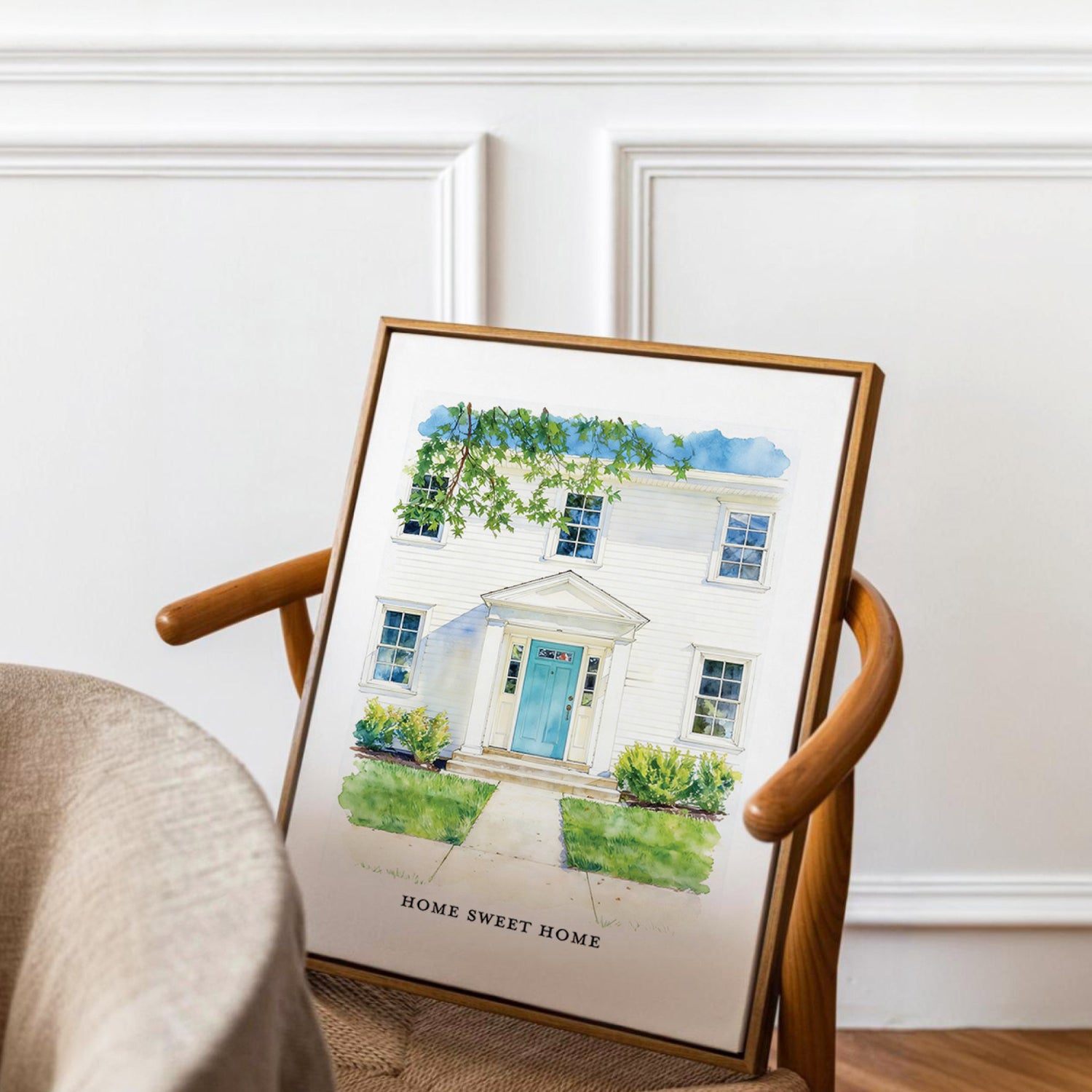 Framed artwork of a custom front door home portrait of a house with 'Home Sweet Home' text on a chair.