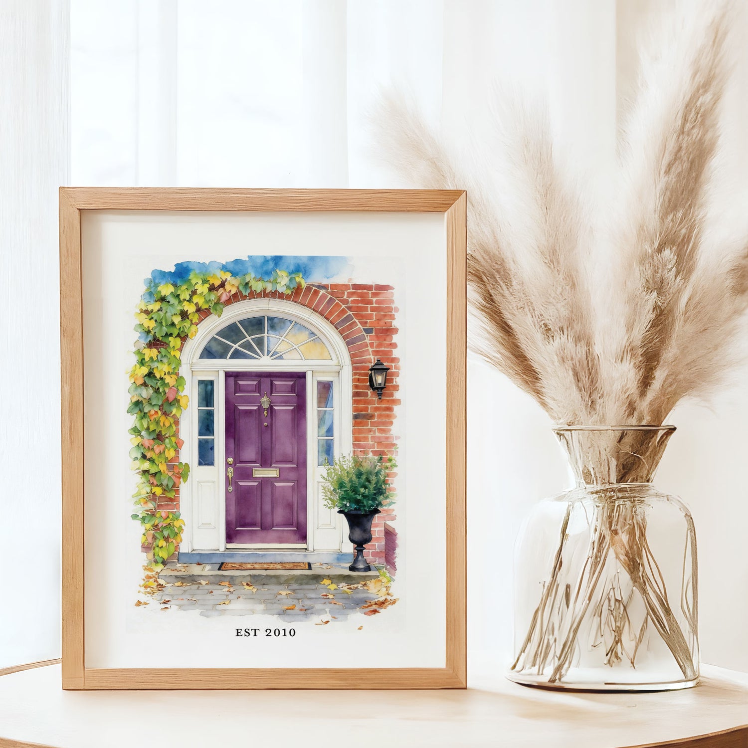 Framed artwork of a custom front door home portrait of a purple door with pampas grass in a vase next to it.