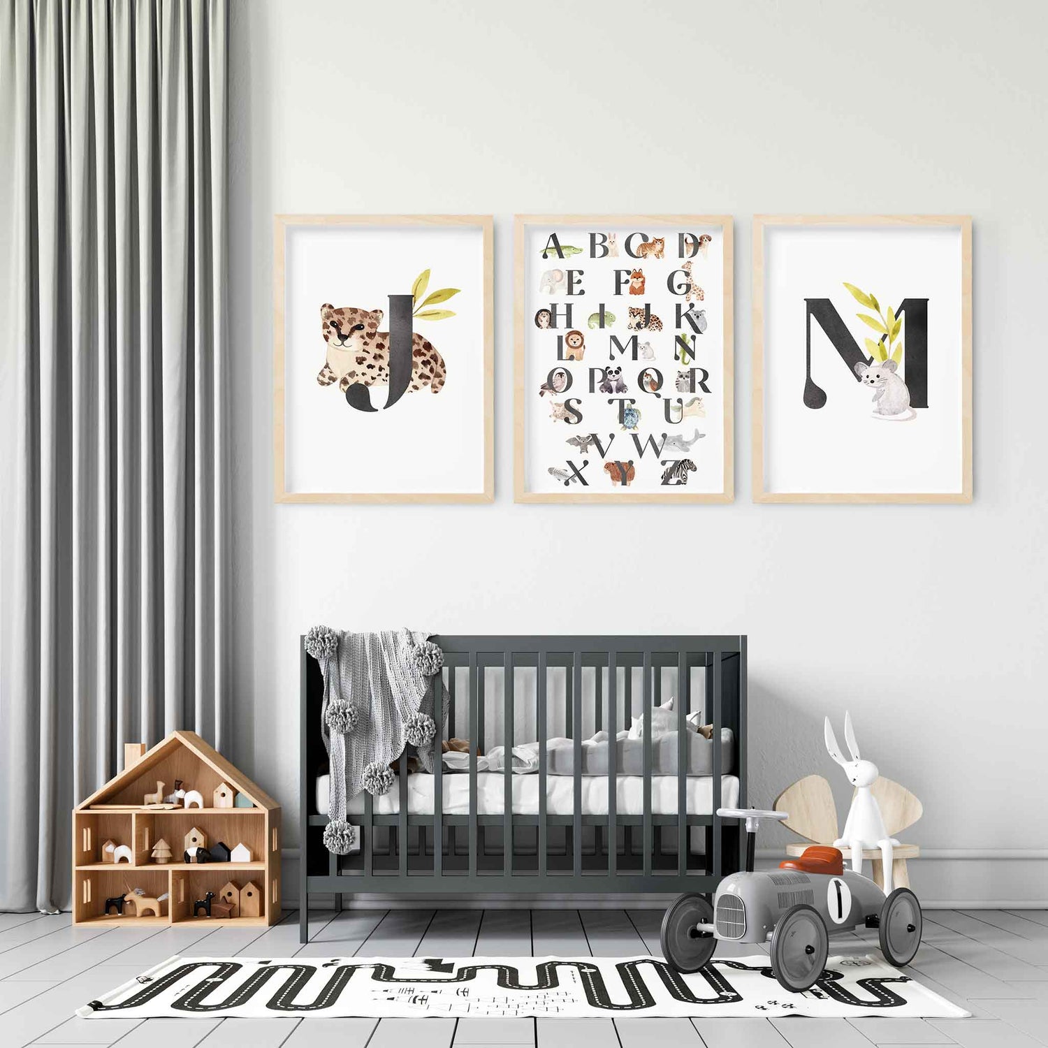 A set of 3 oak picture frames of black monogram prints and alphabet shape animal chart displayed in a nursery