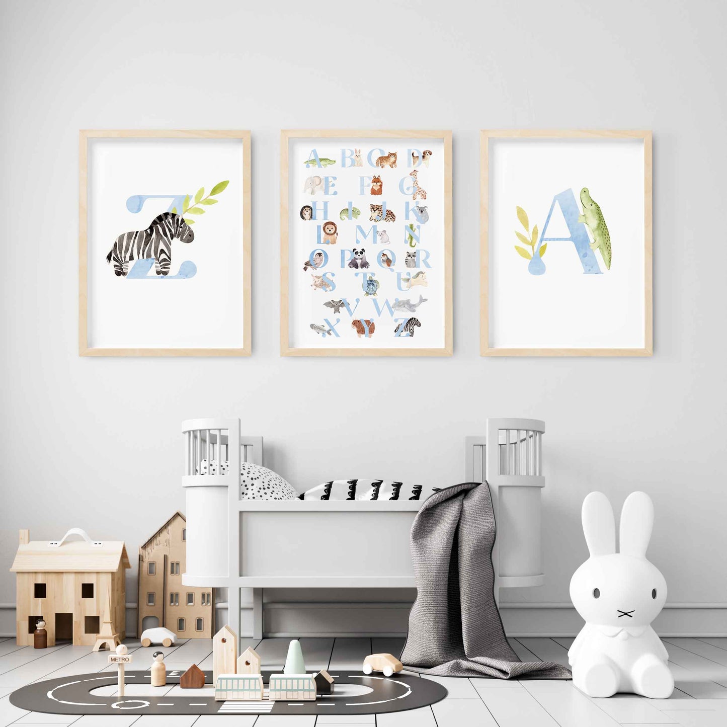 A set of 3 oak picture frames of blue monogram prints and alphabet shape animal chart displayed in a nursery