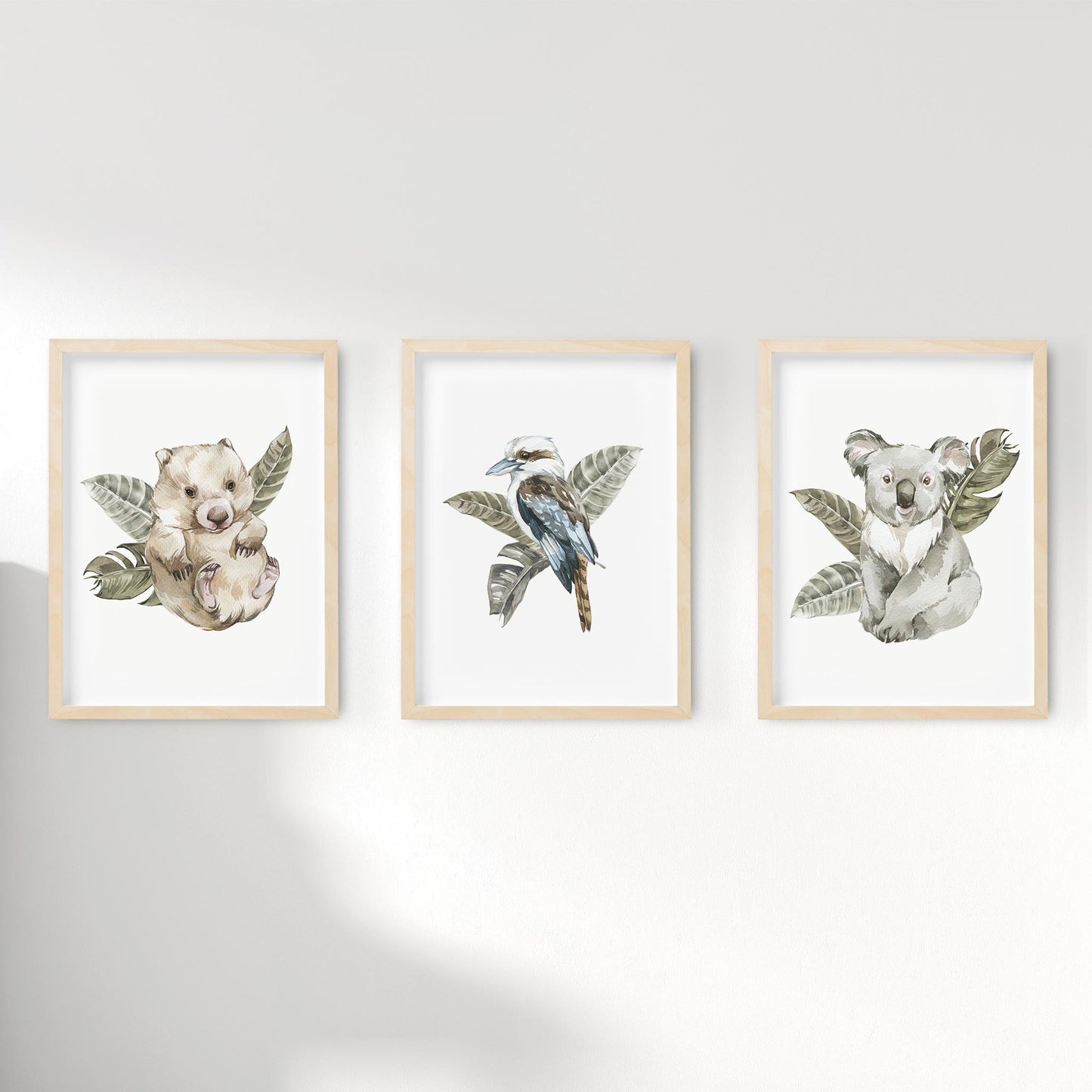 A set of 3 framed oak frames displaying kids nursery wall prints of Australian wombat, kookaburra and koala with leaves background