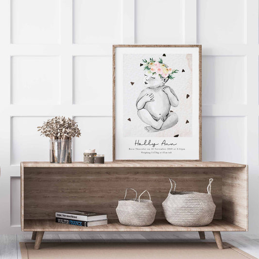 An oak picture frame of a baby girl personalised birth poster print decorated in a living room