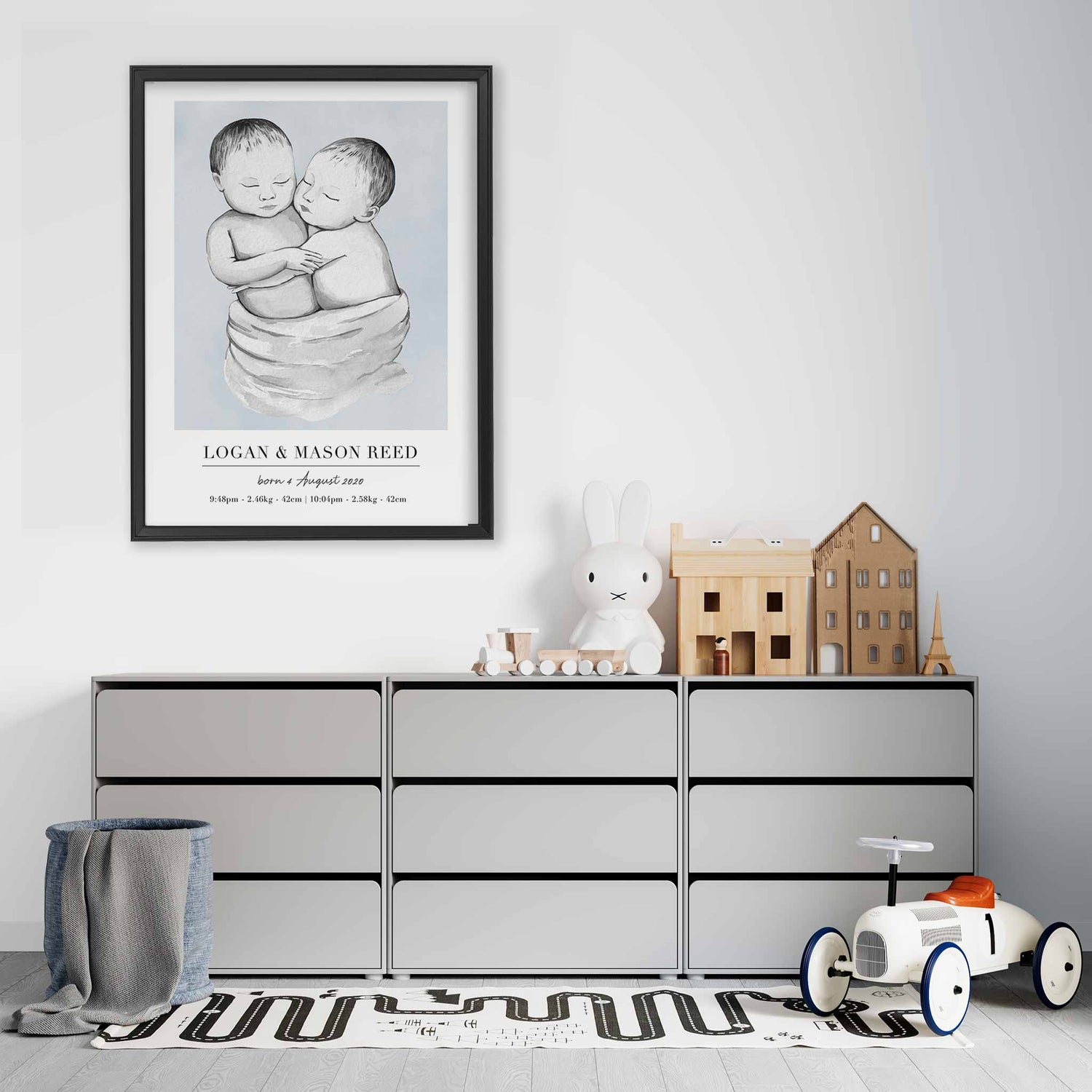 A black picture frame of a baby twin boys personalised birth poster print decorated in a living room