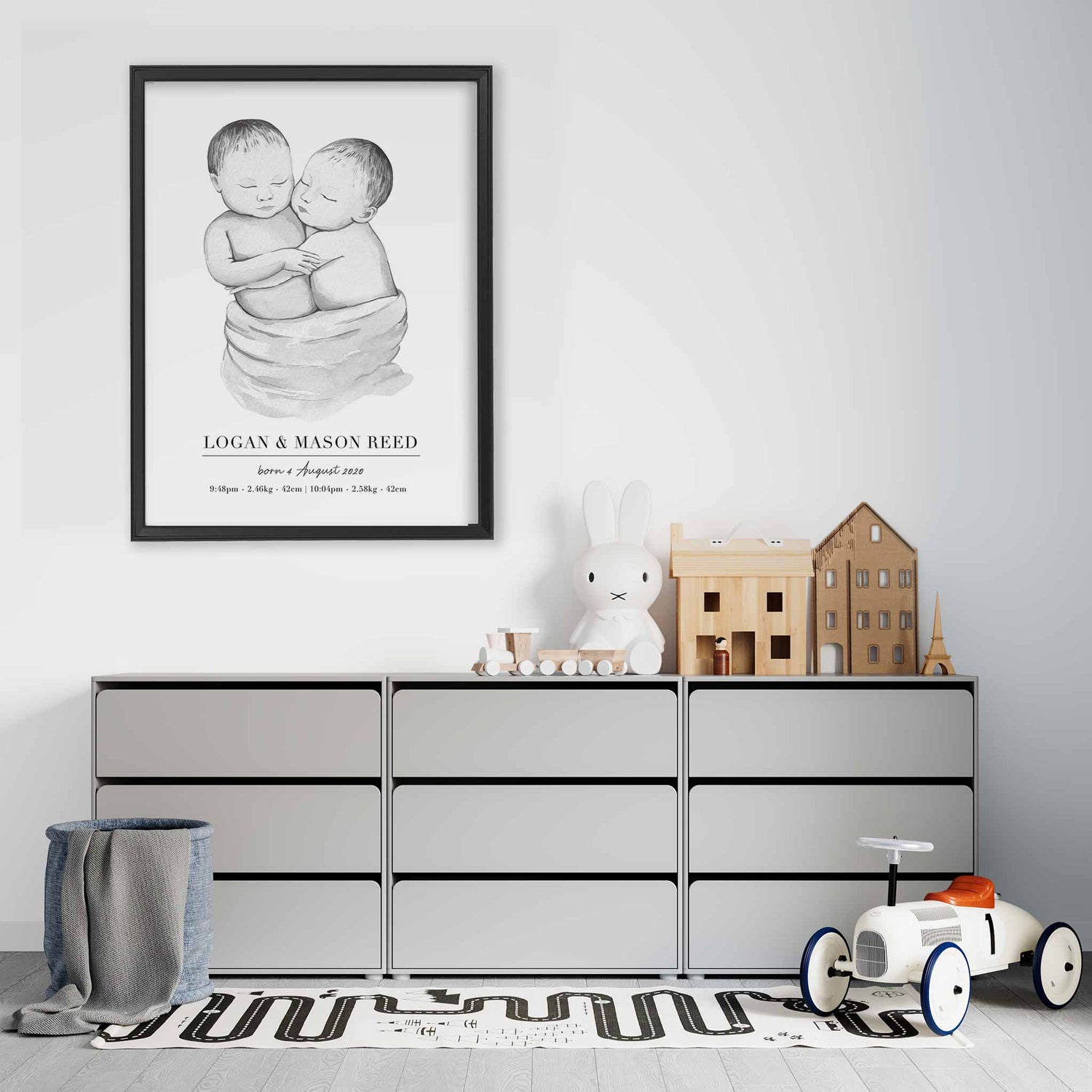 A black picture frame of a baby twin boys personalised birth poster print decorated in a living room