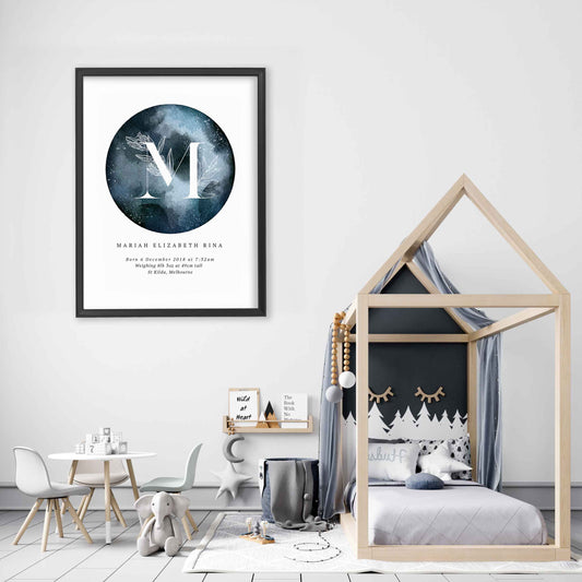 A black picture frame of a dark blue moon with a floral letter monogram and personalised birth print details in a girl's bedroom