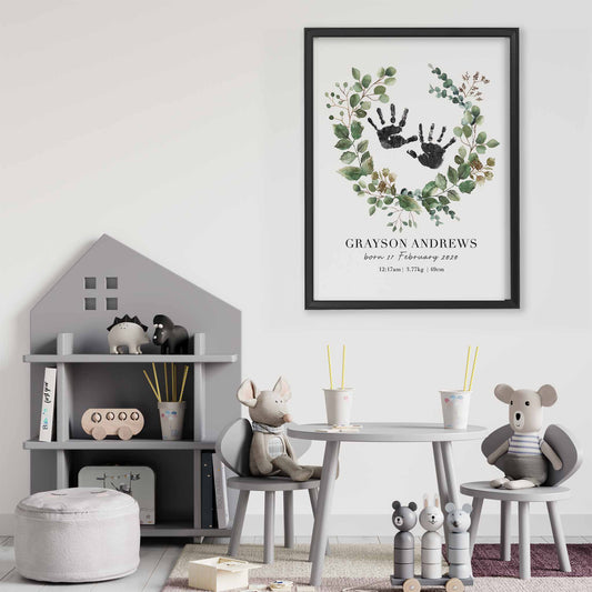 A black picture frame of a botanical baby personalised keepsake handprints birth print decorated in a nursery