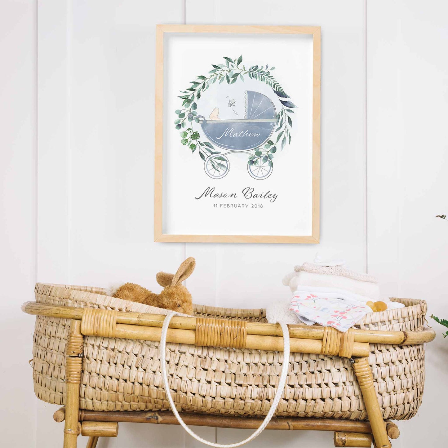 An oak picture frame of a botanical wreath baby pram personalised birth print decorated in a nursery