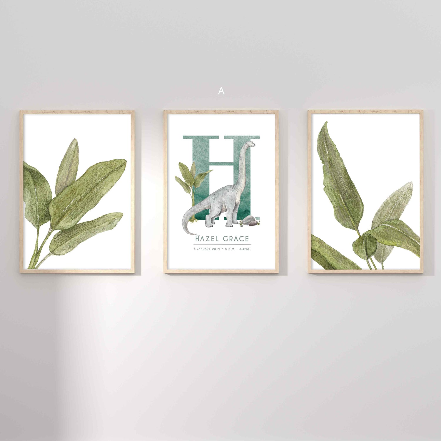 A set of 3 framed oak frames displaying kids nursery wall prints of palm leaves and a dinosaur personalised monogram birth print