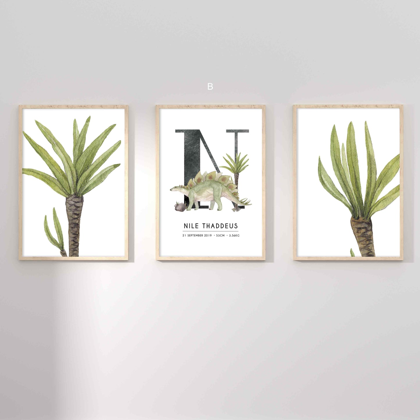 A set of 3 framed oak frames displaying kids nursery wall prints of palm leaves and a dinosaur personalised monogram birth print