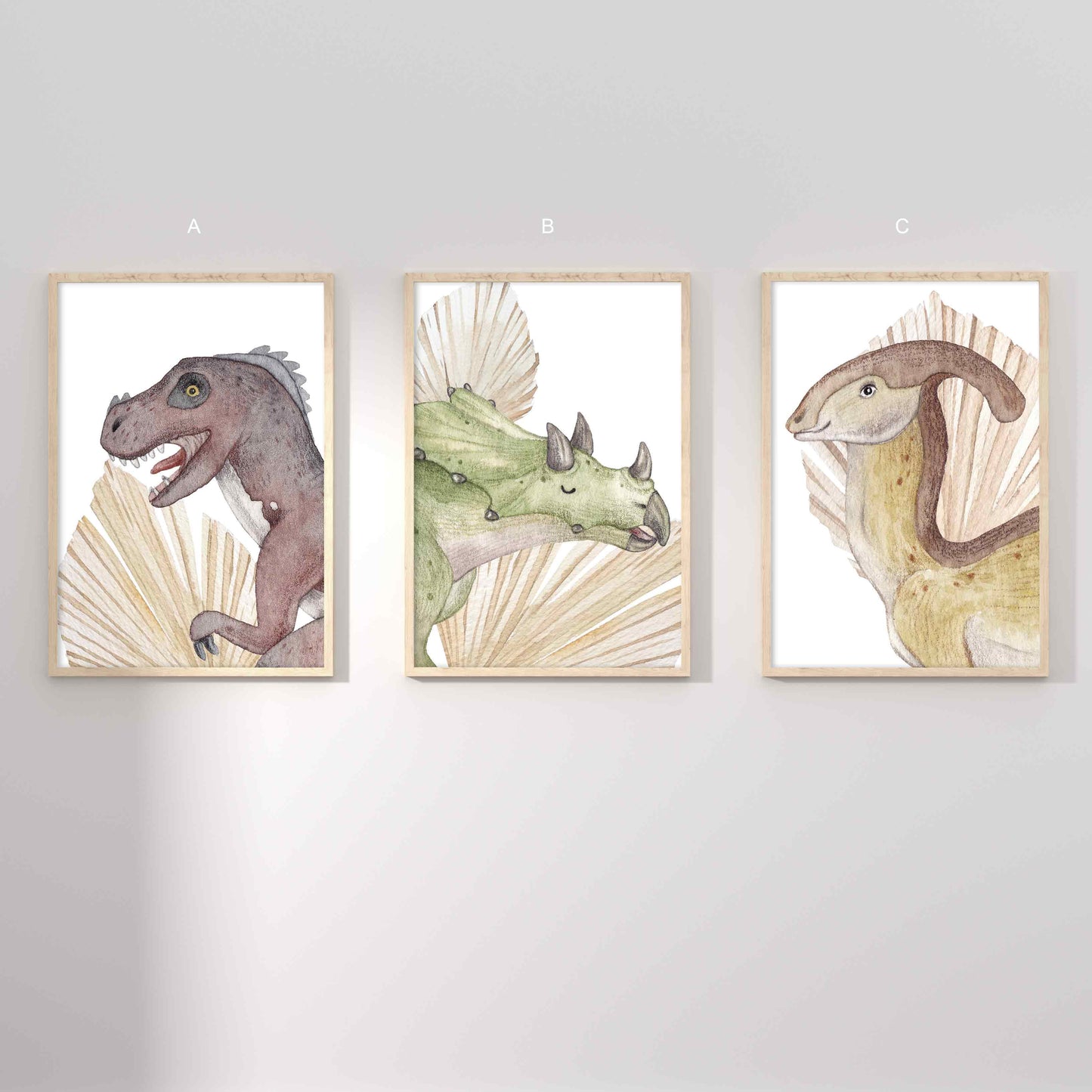 A set of 3 framed oak frames displaying kids nursery wall prints of dinosaurs and dried palm leaves