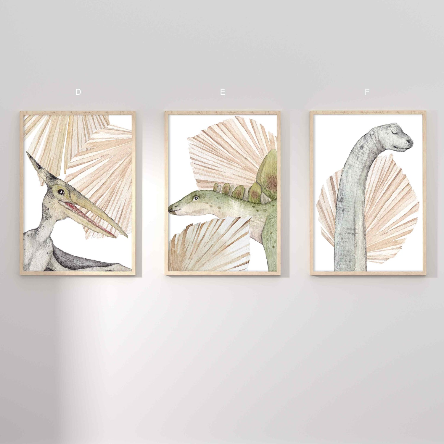 A set of 3 framed oak frames displaying kids nursery wall prints of dinosaurs and dried palm leaves