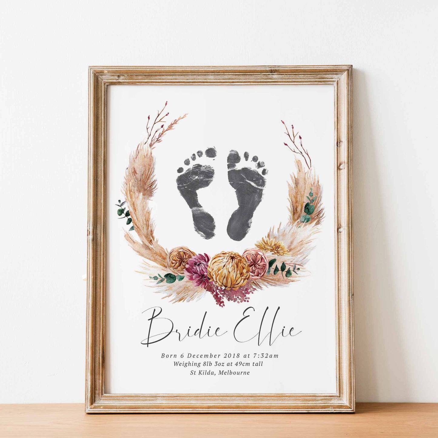 An oak picture frame of a floral boho baby personalised keepsake footprints birth print