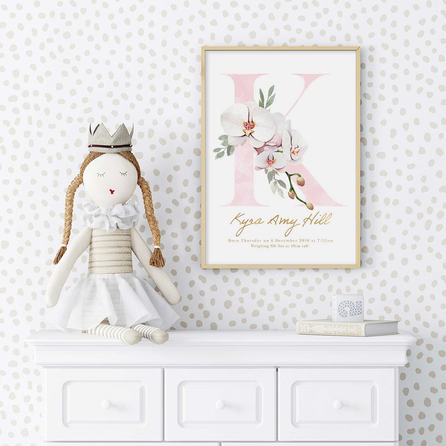 A white frame of floral orchid pink gold monogram nursery personalised birth print decorated in a nursery