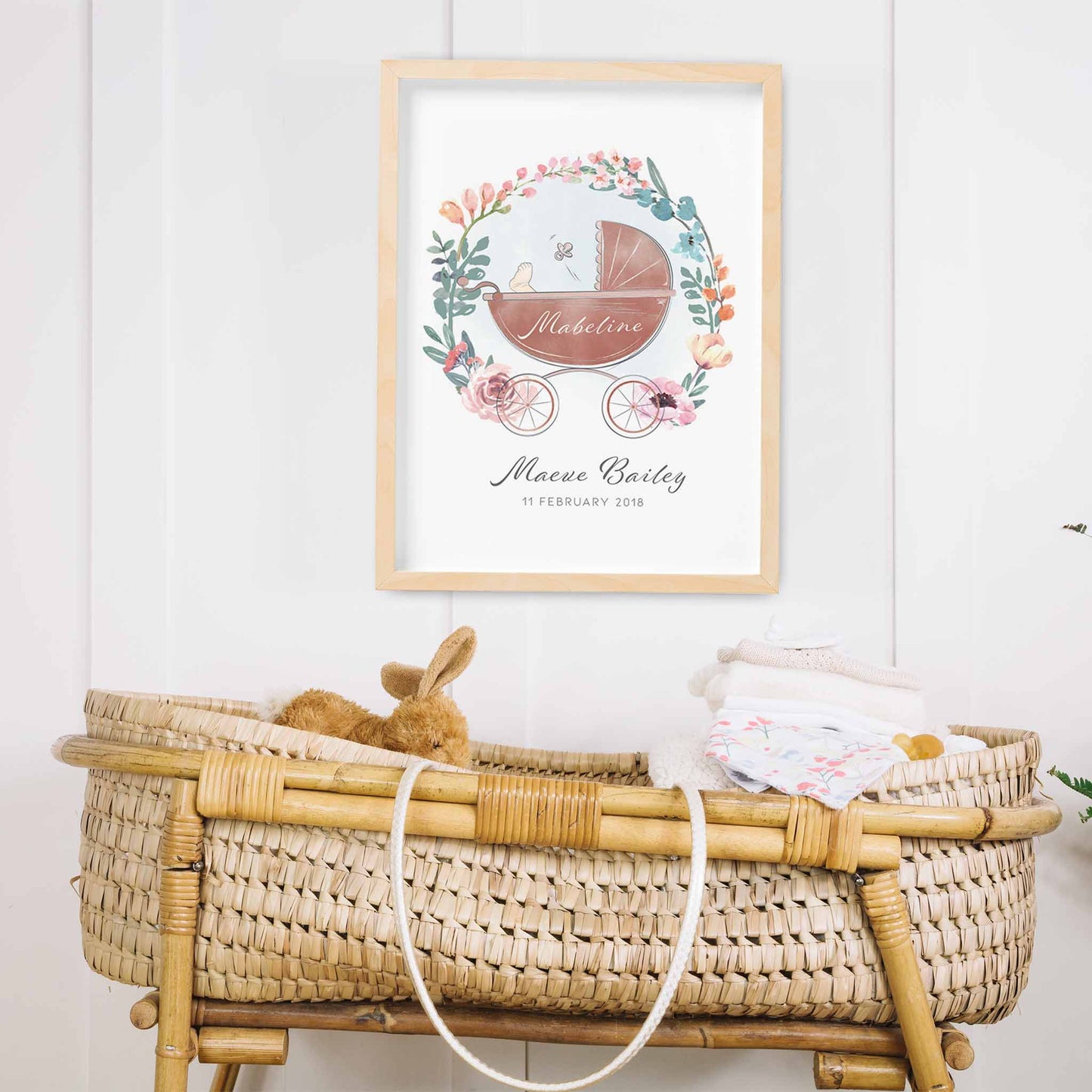 An oak picture frame of a floral wreath baby pram personalised birth print decorated in a nursery