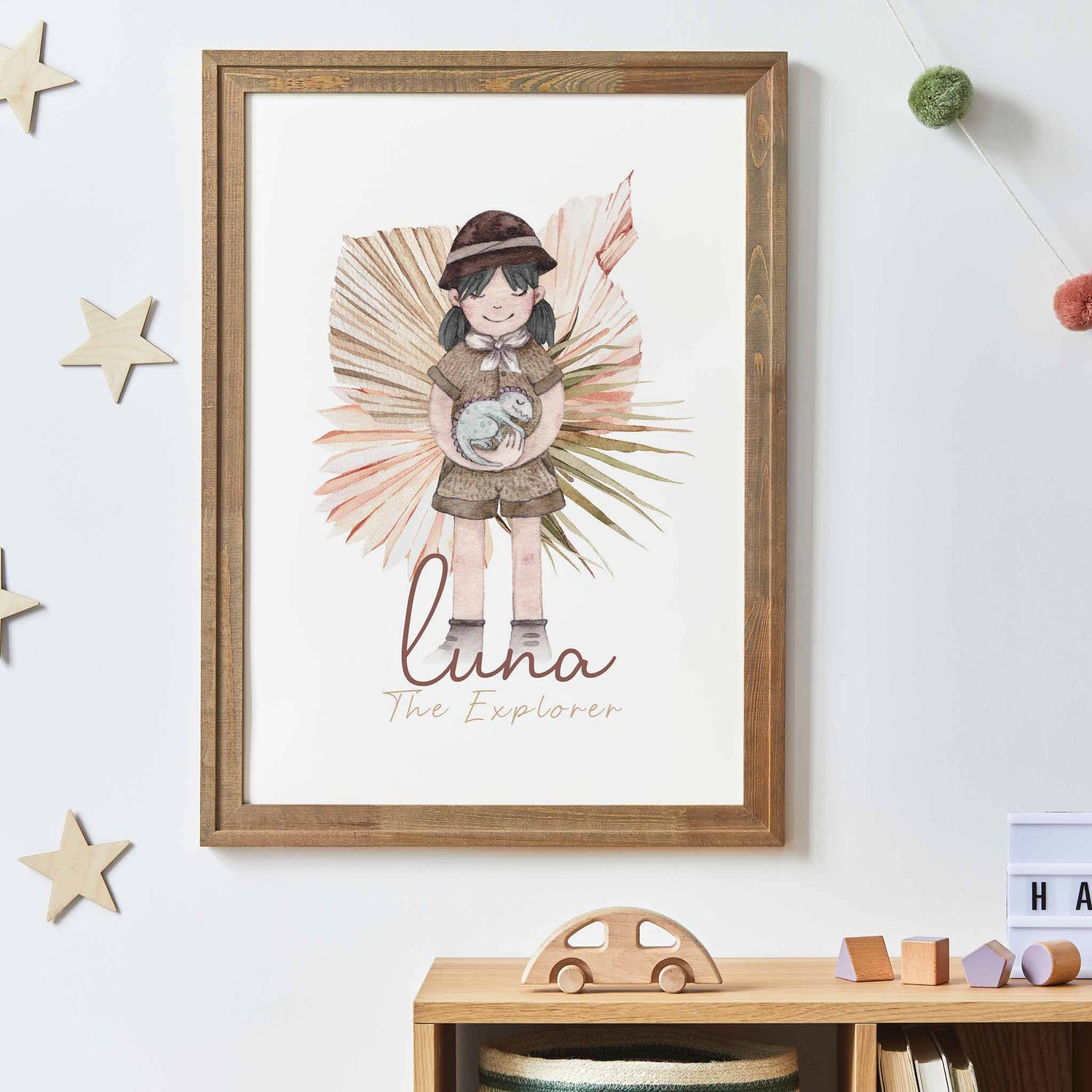 A picture frame of a black haired little girl holding a baby dinosaur displayed on the wall of a kids room