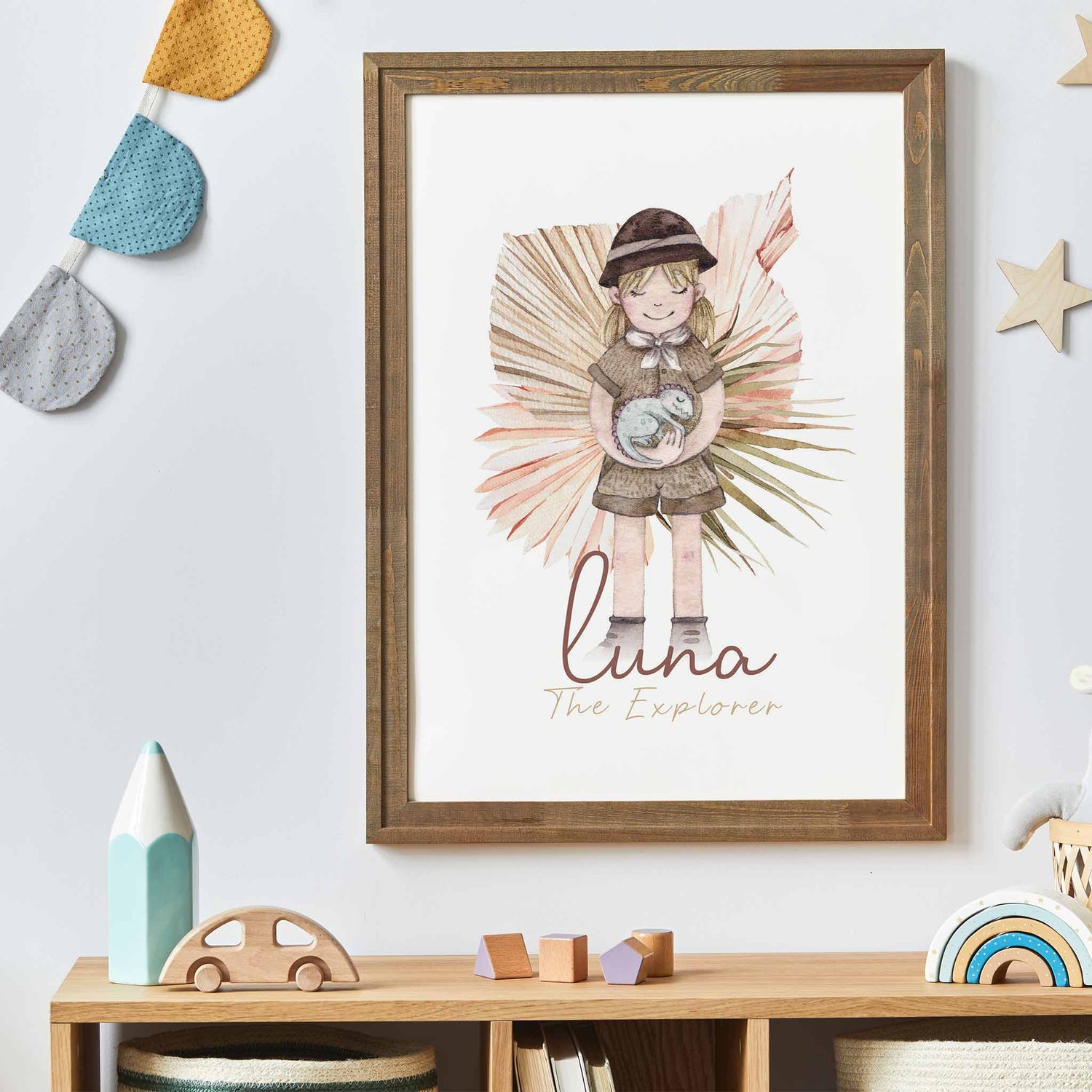 A picture frame of a blonde haired little girl holding a baby dinosaur displayed on the wall of a kids room