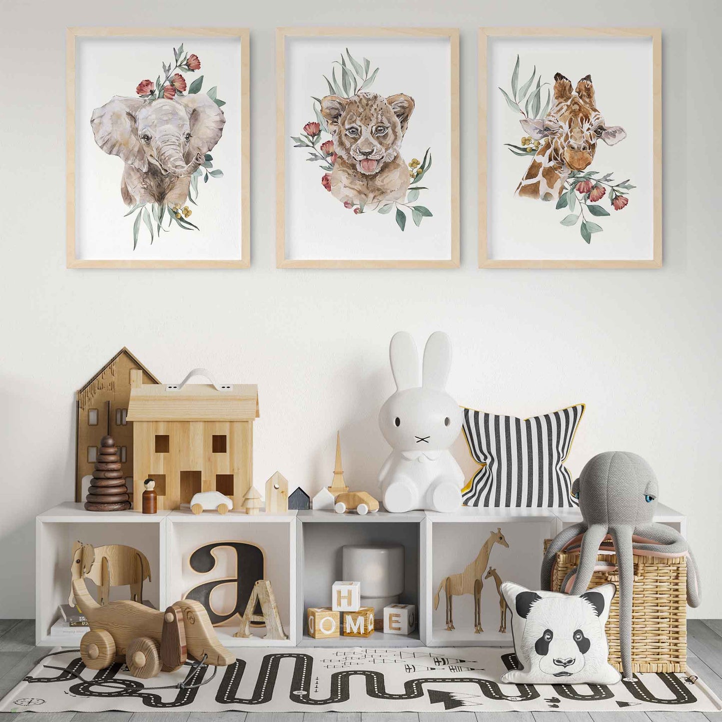 A set of 3 wall oak framed images of baby safari animals elephant, lion and giraffe displayed on the wall of a kids playroom